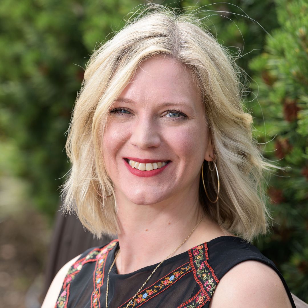 Headshot of Gail Robertson, who stands in front of a green background and wears a black top.