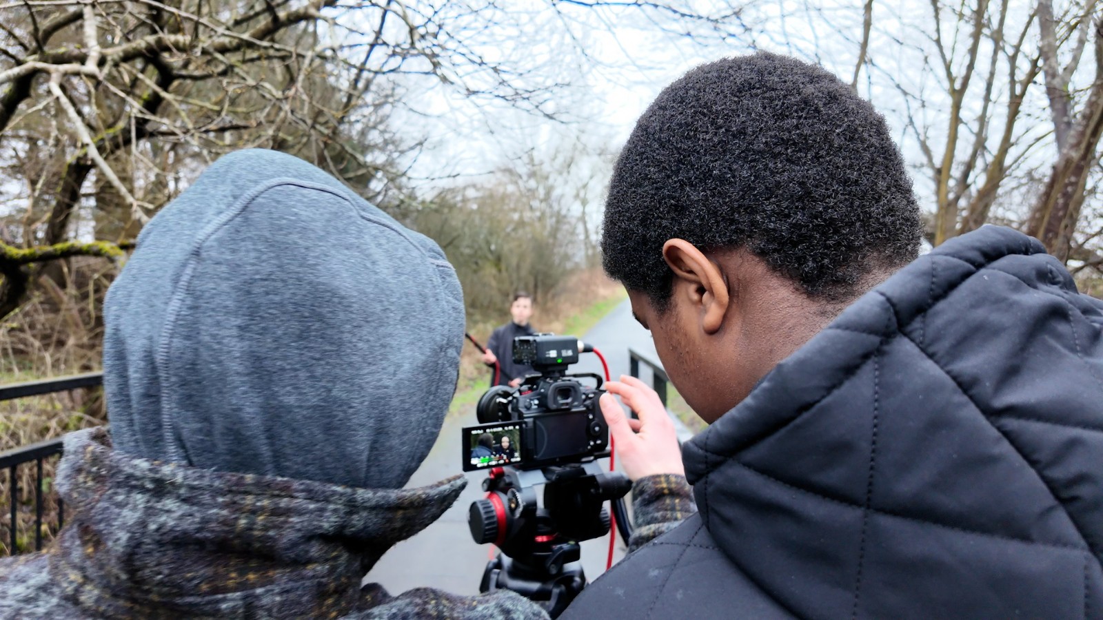 Two of the attendees of the Police Scotland Youth Volunteers screen education programme in Dunfermline. Their heads face away, looking at the camera on a tripod in a park.