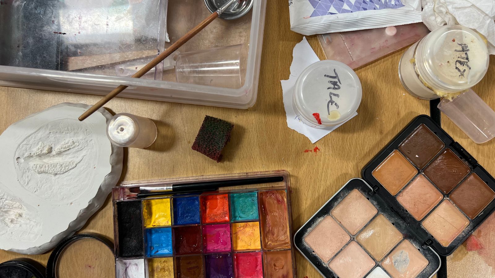 A mix of make up palettes and special effects items lie on a table.