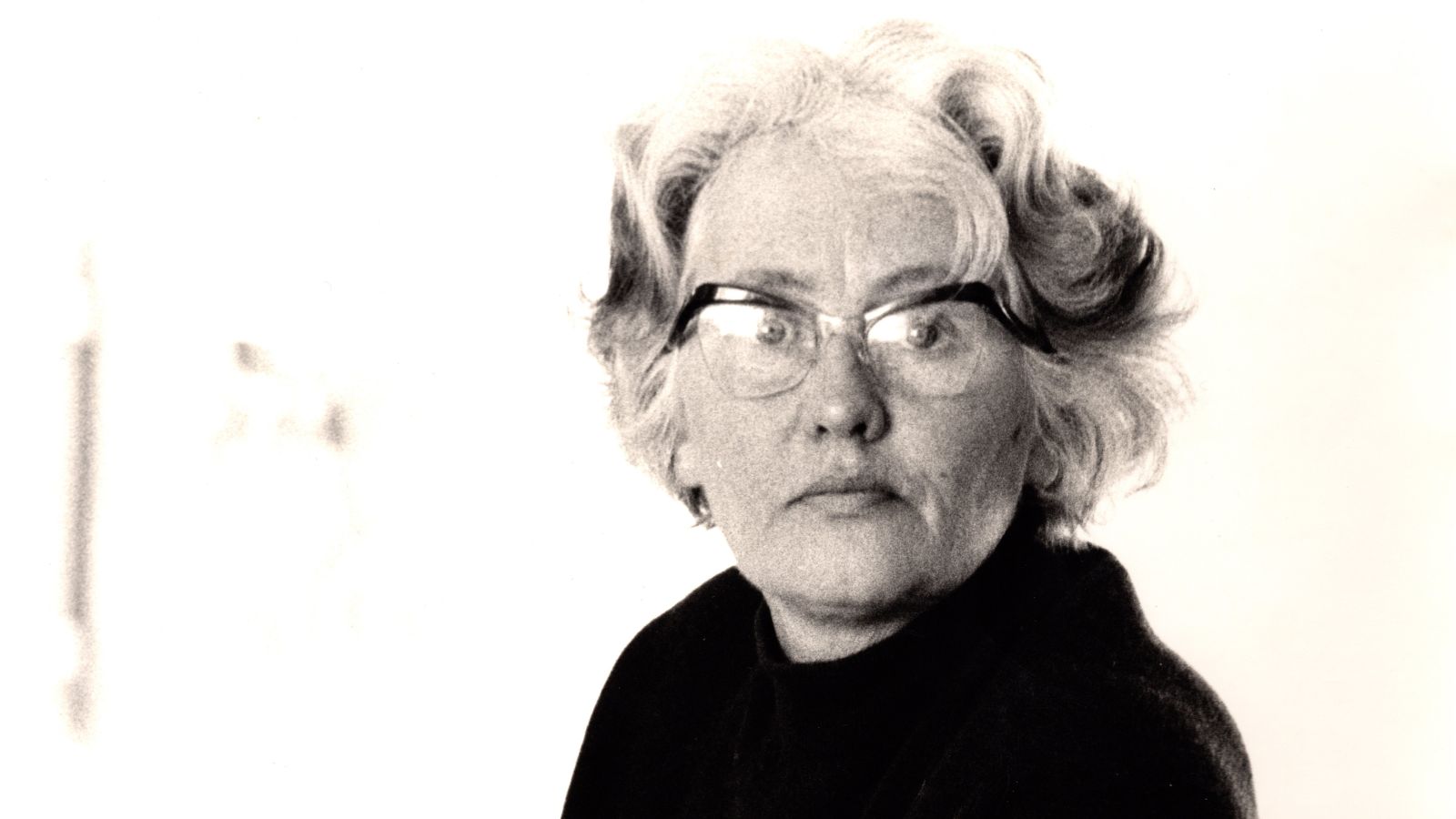 Black and white image of Wilhelmina Barns-Graham, whe is shown from the shoulders up, and wears glasses and a black top. credit Ander Gunn