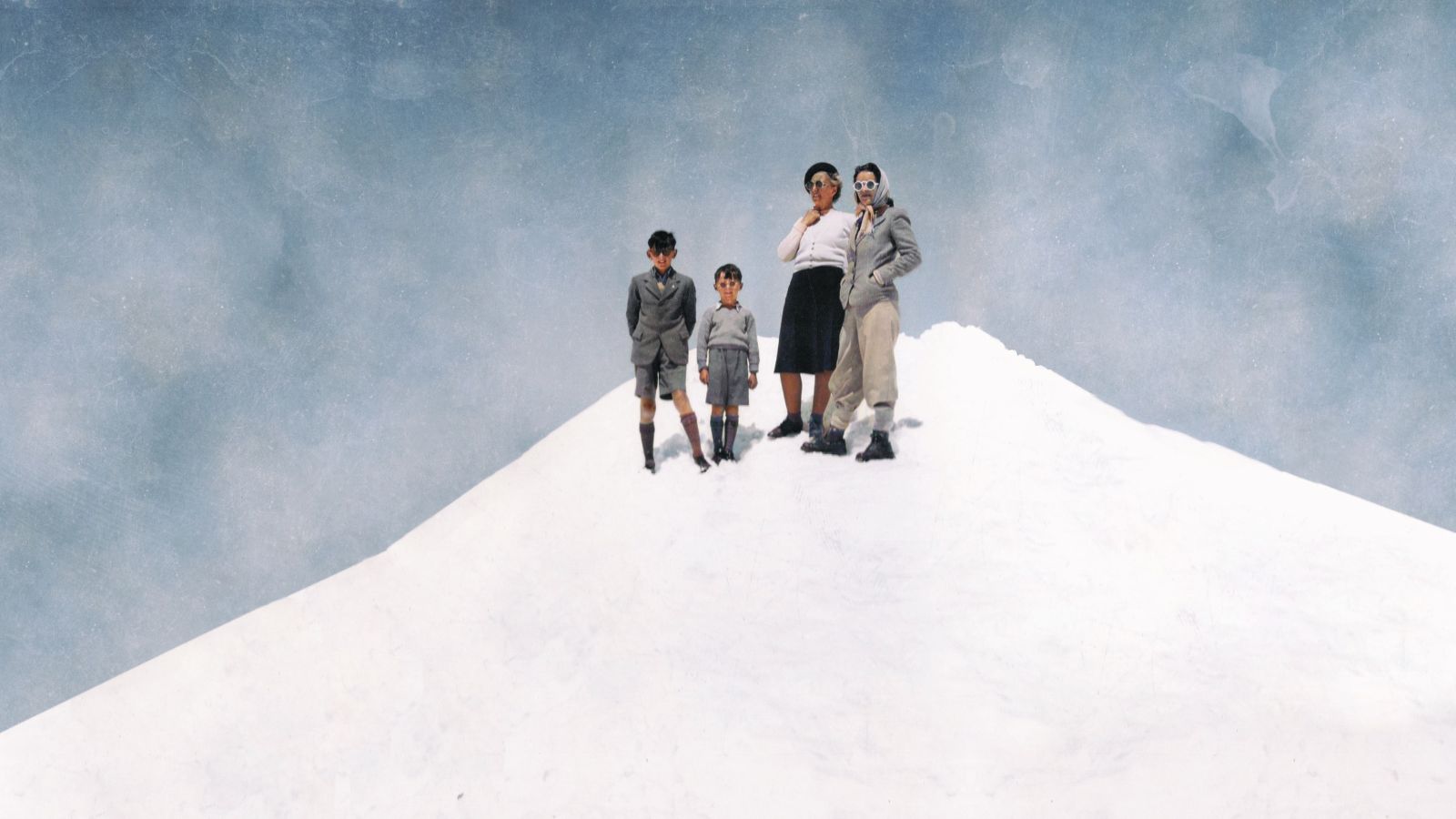 Image shows two children and two adults standing side by side on a white patterned floor. Around them is blue, which gives the impression that the stand on a white mountain top.