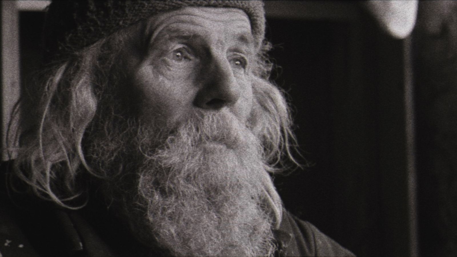 Still from Bogancloch, which shows a black and white image of the close up of a man's face. He has a beard and long hair.