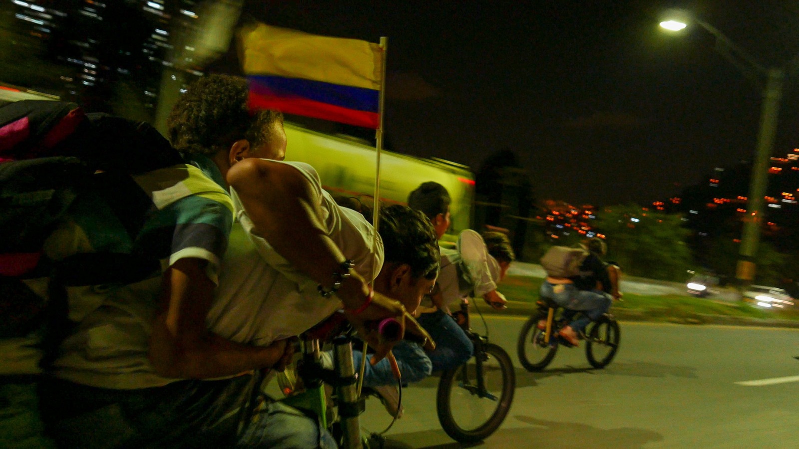 Several cyclists ride at speed at night