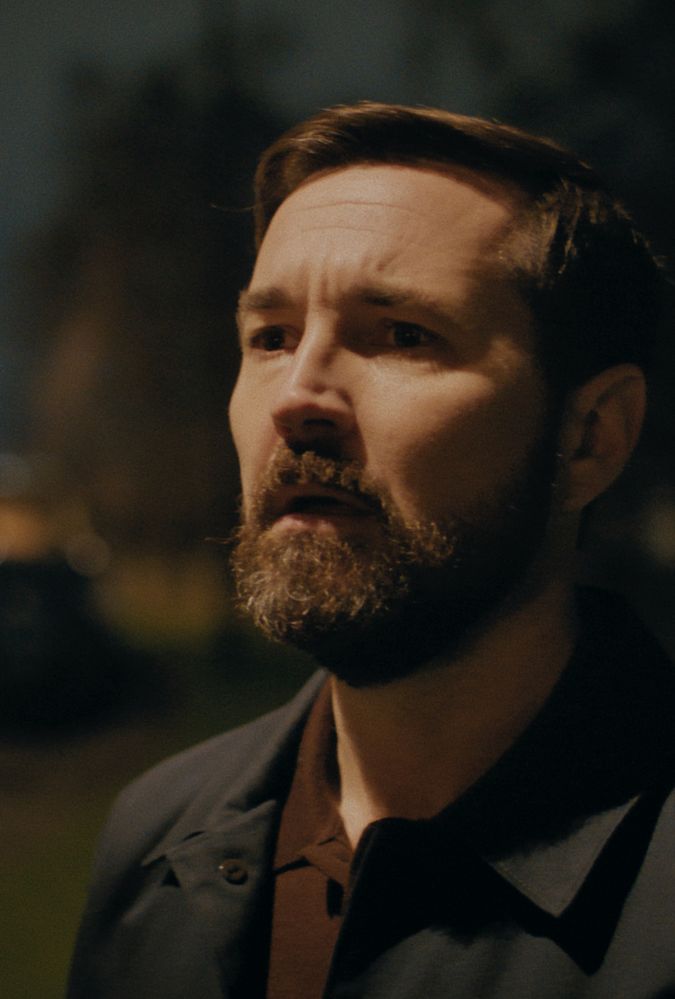 Still from Fear, courtesy of Prime Video. Actor Martin Compston stands outdoors in a residential street at night.