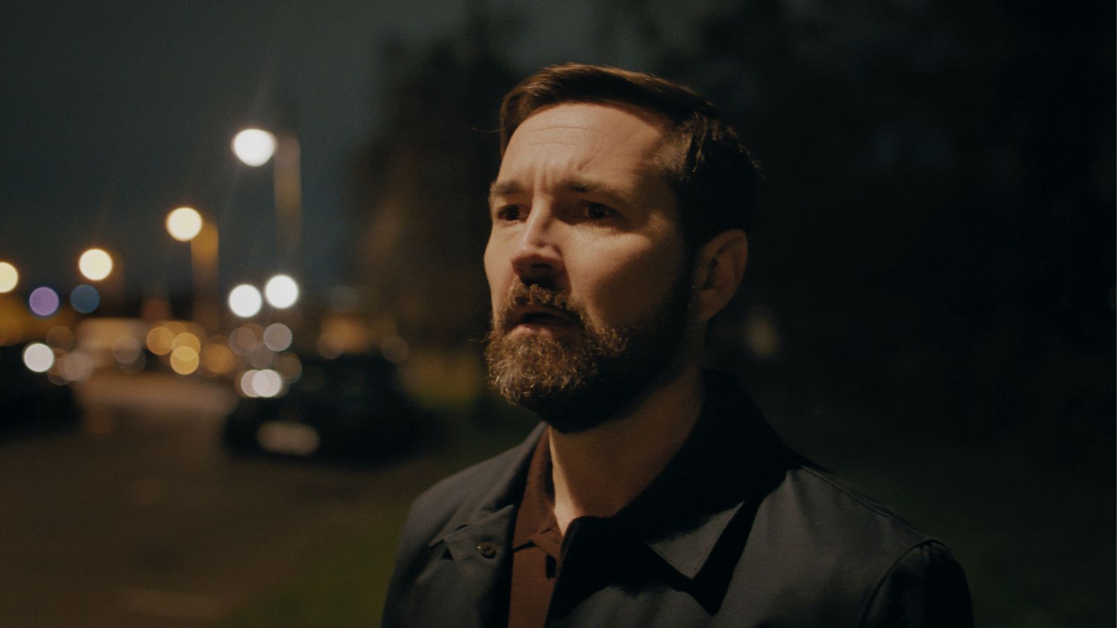 Still from Fear, courtesy of Prime Video. Actor Martin Compston stands outdoors in a residential street at night.