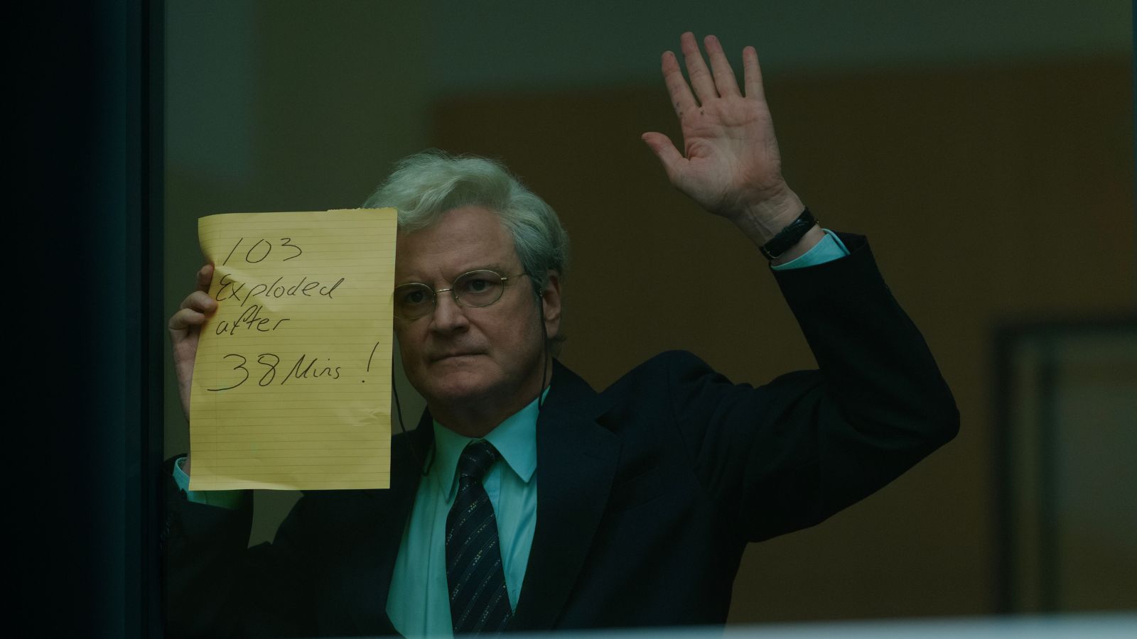 Still from Lockerbie, showing Colin Firth in a suit, holding up a piece of paper against a window. The paper reads 103 exploded after 38 mins!