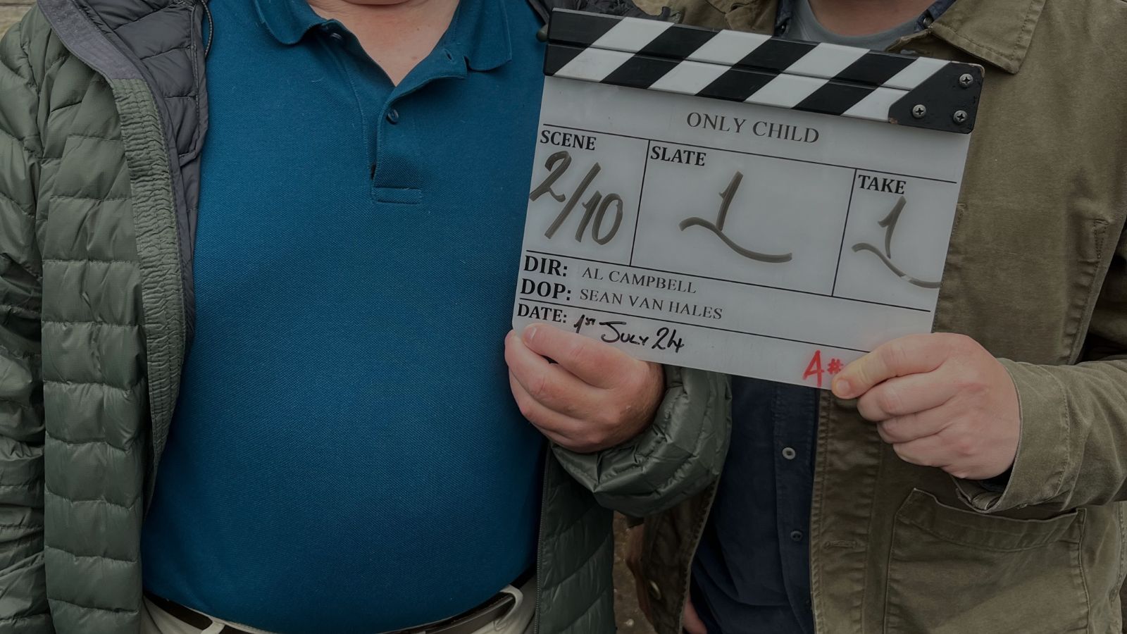 Gregor Fisher and Greg McHugh are shown from the shoulders down holding a clapper board, which is for Only Child. They stand outside in front of a brick wall.