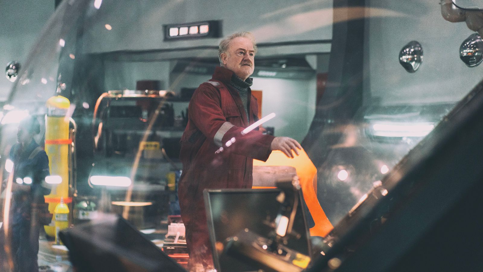 Still from the Rig season 2 showing a man in an orange boiler suit in a control room on an oil rig.