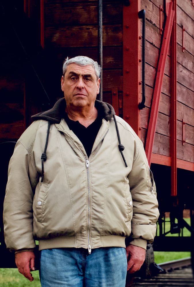 Gary Sokolov stands in front of a red train carriage outside of Auschwitz Birkenau