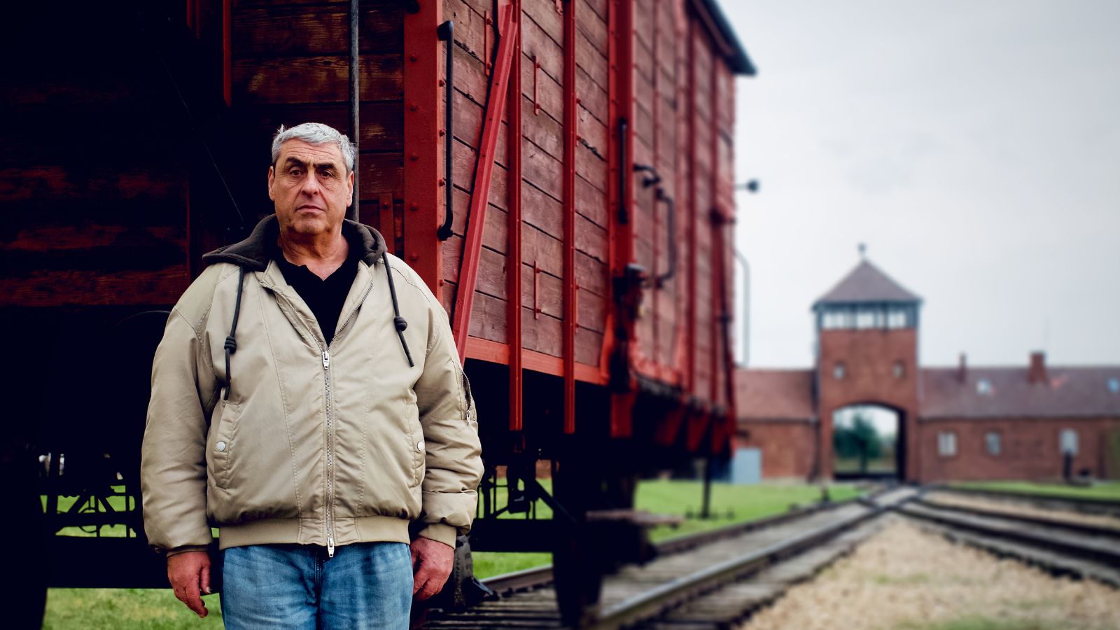 Gary Sokolov stands in front of a red train carriage outside of Auschwitz Birkenau