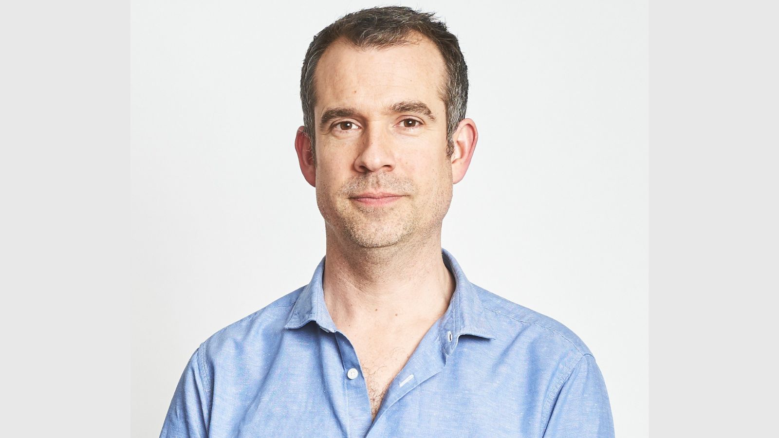 Headshot of Dr Chris van Tulleken, who wears a light blue shirt.