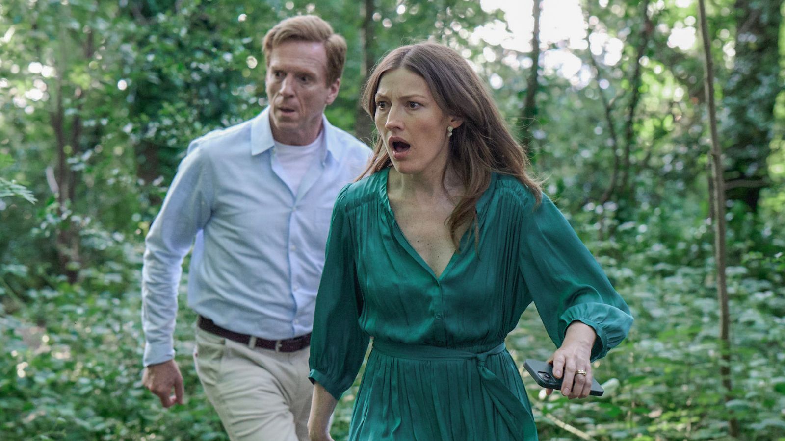 Still from The Radleys, which shows actors Damian Lewis and Kelly Macdonald running through a wood during the day, they look shocked.