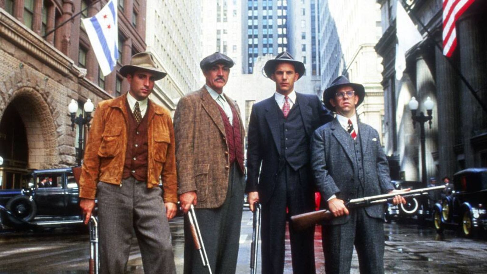 Still from The Untouchables, which shows actors Andy Garcia, Sean Connery, Kevin Costner and Charles Martin Smith standing in a line with New York in the background. They wear 1930s clothes and carry shotguns.