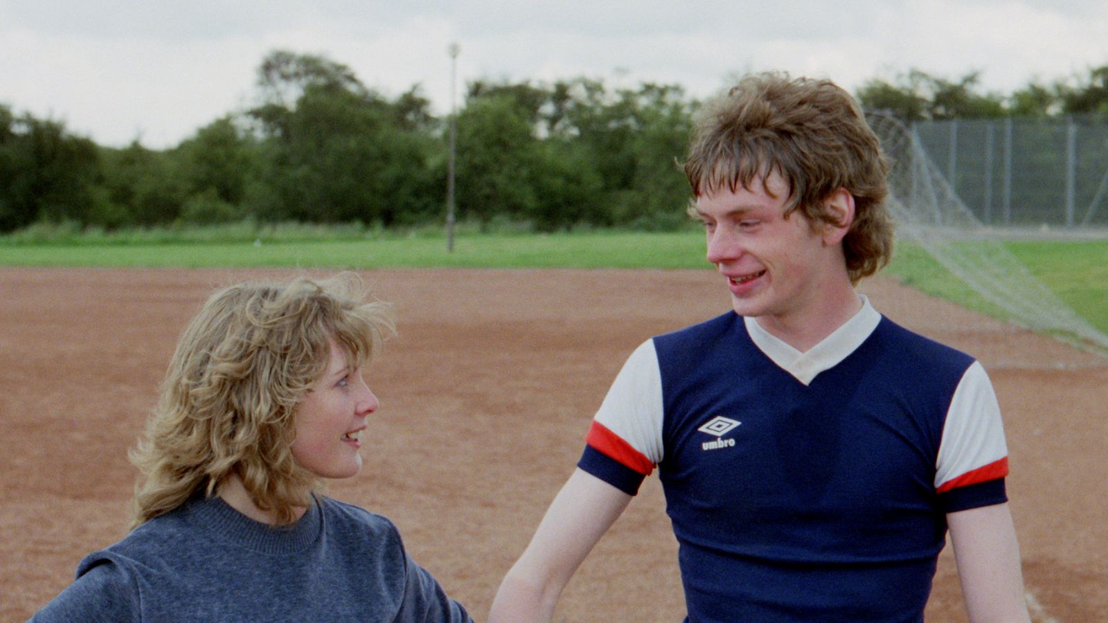 Still from Gregory's Girl, showing actors Dee Hepburn and John Gordon Sinclair standing on a football pitch in Scotland.