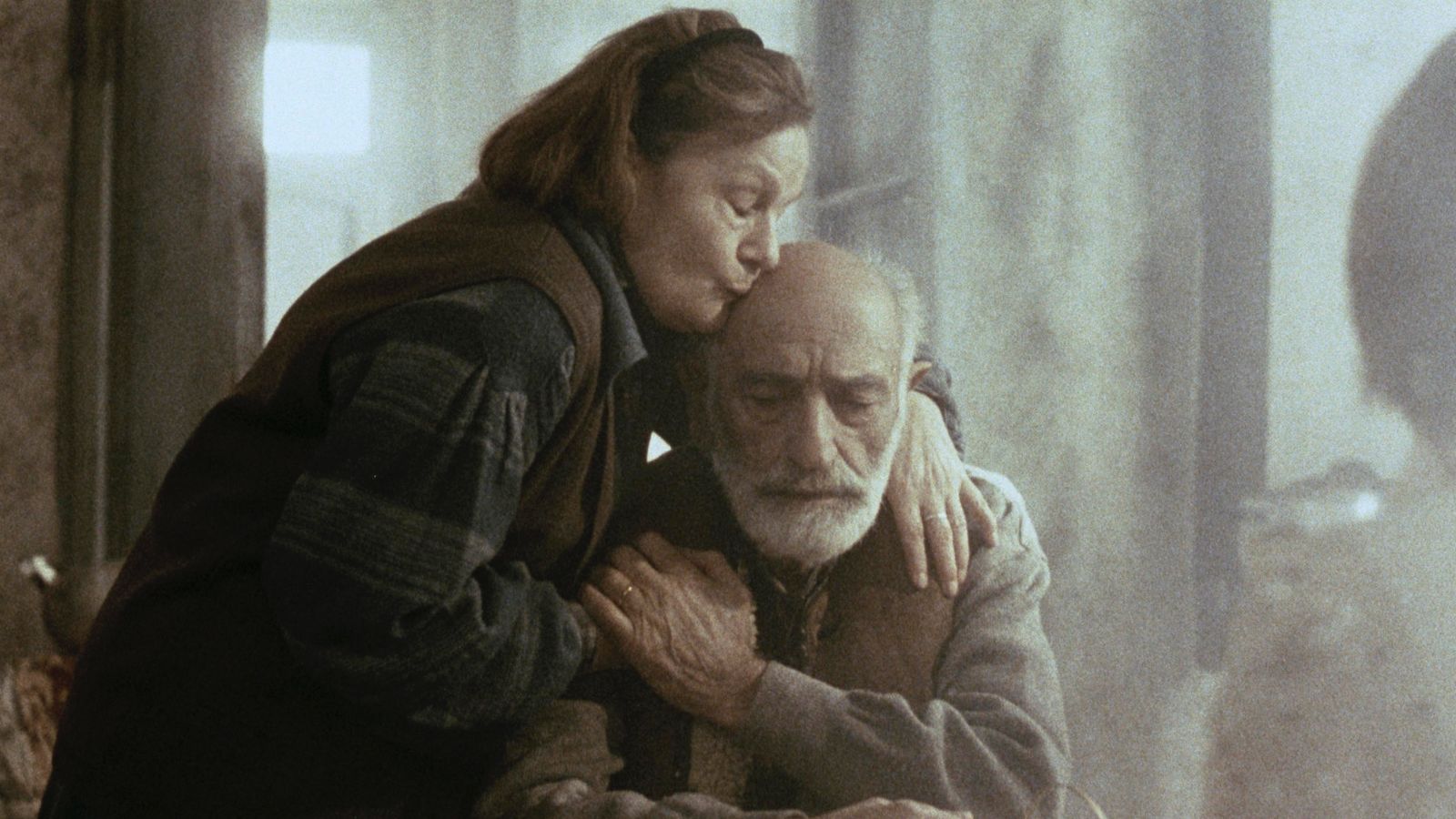 Still from Lighthouse, showing an older man and woman embracing by a window.