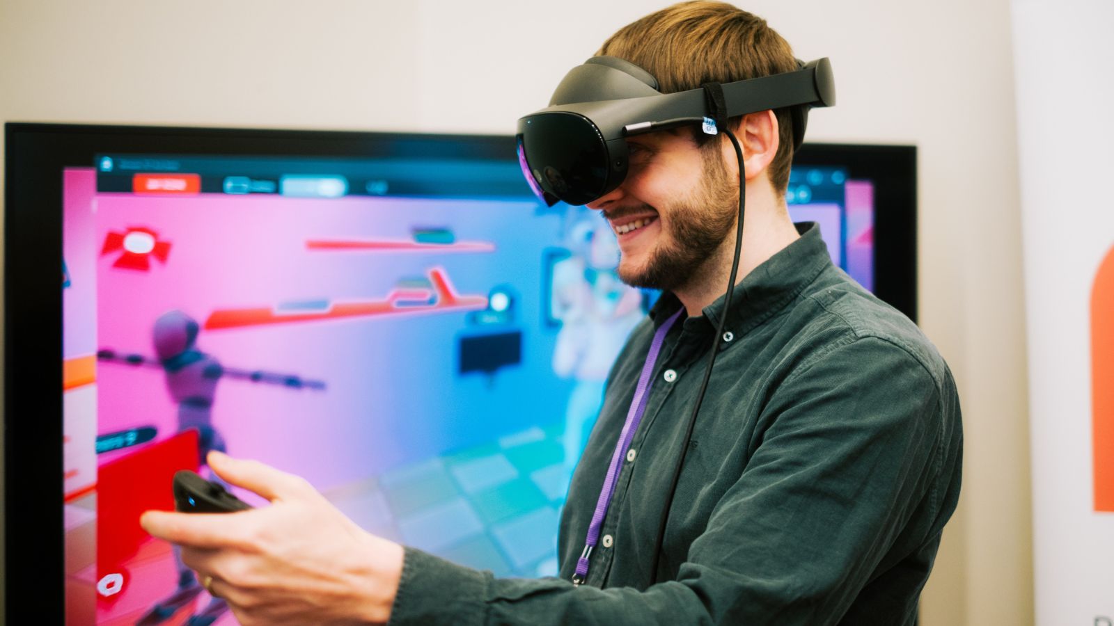 Image from MOVE Summit 2024 showing a man wearing a VR headset. He stands in front of a TV screen.