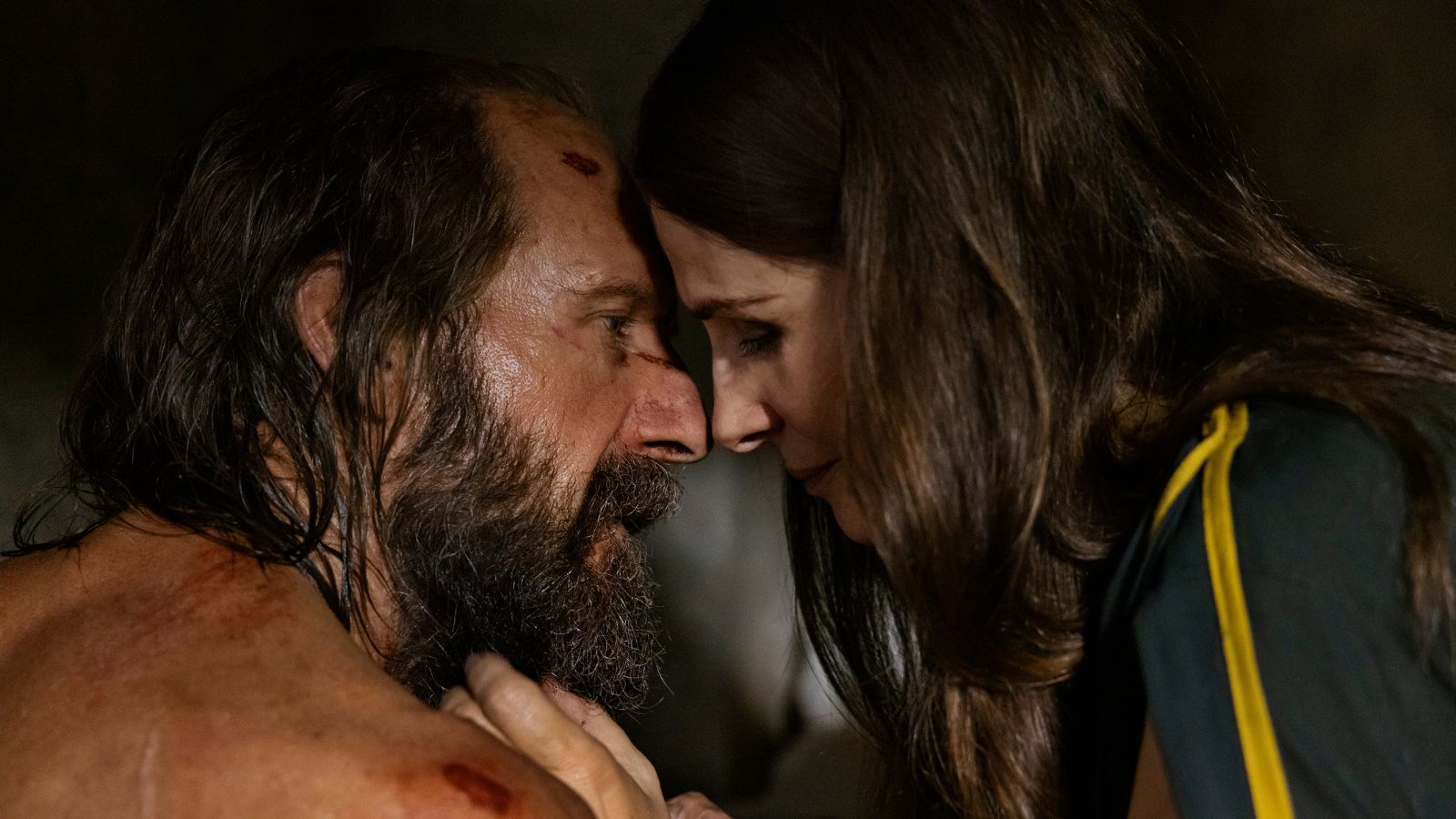 Still from The Return, which shows actors Ralph Fiennes and Juliette Binoche with their foreheads touching. Ralph Fiennes is covered in cuts and bruises.